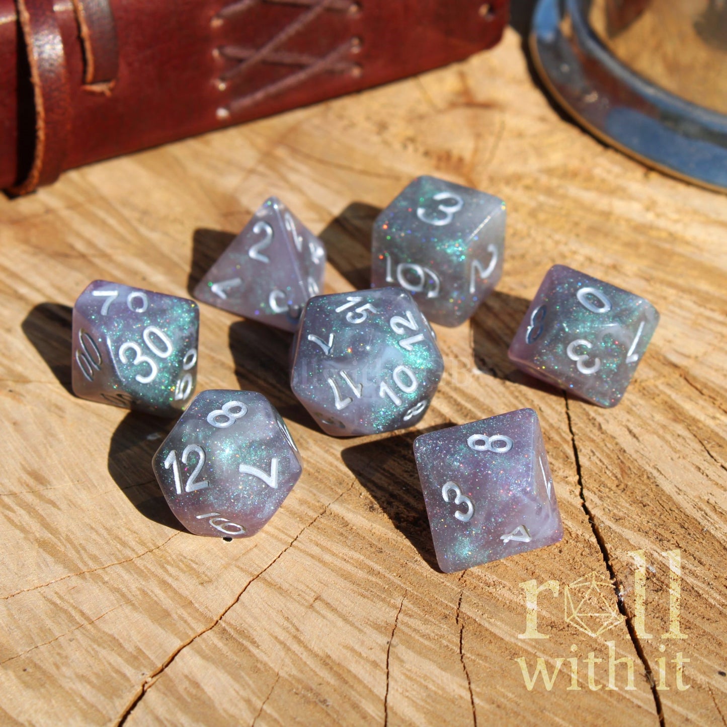 Set of silver galaxy purple D&D dice on a wooden surface with 'roll with it' text
