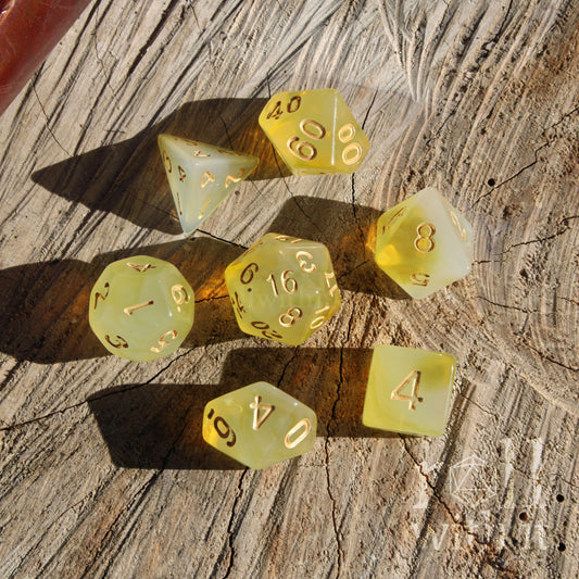 Set of 7 yellow polyhedral tabletop roleplaying gamer dice on a wooden surface