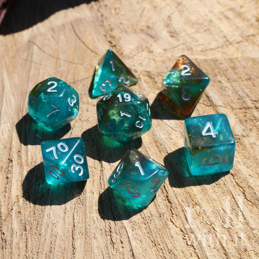 Set of 7 glow in the dark resin teal polyhedral TTRPG gaming dice on a wooden surface