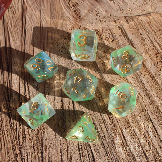 Set of cool breezy green clear water polyhedral dice with gold numbers on a wooden surface
