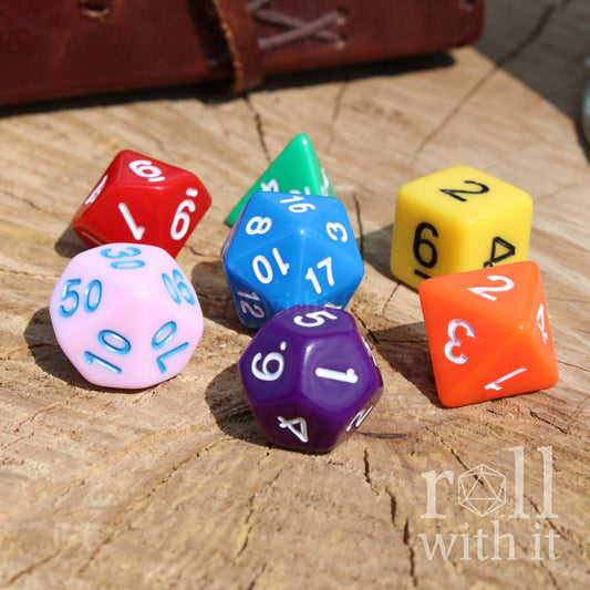 Colorful rainbow multiple polyhedral dice on a wooden surface with 'roll with it' branding.