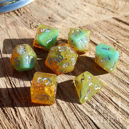 Set of colorful polyhedral dungeons and dragons dice with gold foil and silver numbers on a wooden surface