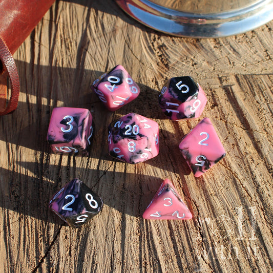 Set of cute pink and black polyhedral dice on a wooden surface
