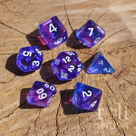 Set of clear indigo purple and blue dice with white numbers on a wooden surface