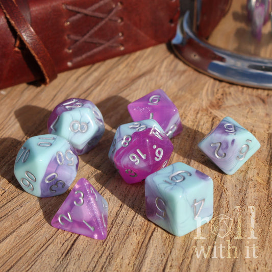Set of purple and light blue polyhedral dice on a wooden surface with 'roll with it' branding.