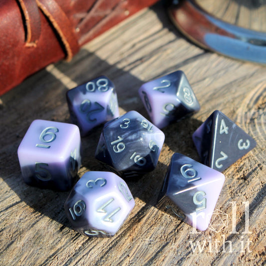 Set of purple and pale dark purple black mixed layered polyhedral dice on a wooden surface