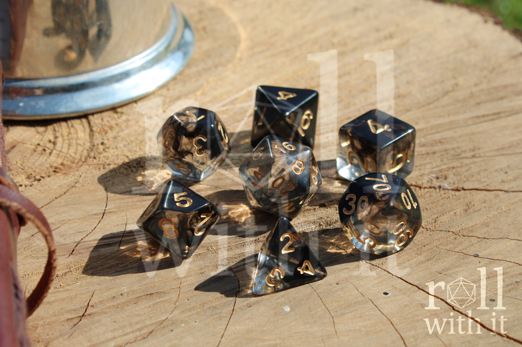 A set of black and clear smoke like polyhedral dice shining on a wooden surface