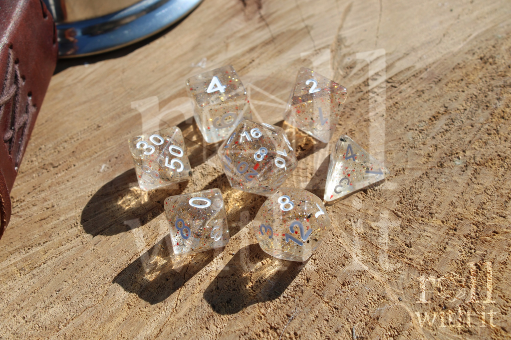 Clear polyhedral roleplaying dice set with orange and black speckles on a wooden surface