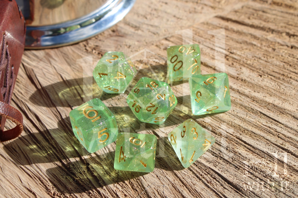 Set of 7 green shimmering polyhedral roleplaying dice with gold numbers on a wooden surface