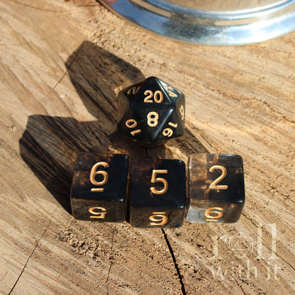 Black swirl DnD dice with gold numbers on a wooden surface