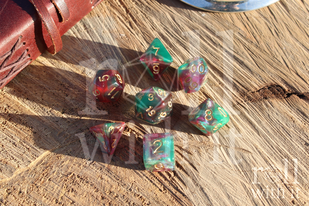 Set of Faerie King polyhedral TTRPG dice with red and green shimmers on a wooden surface with a leather case.