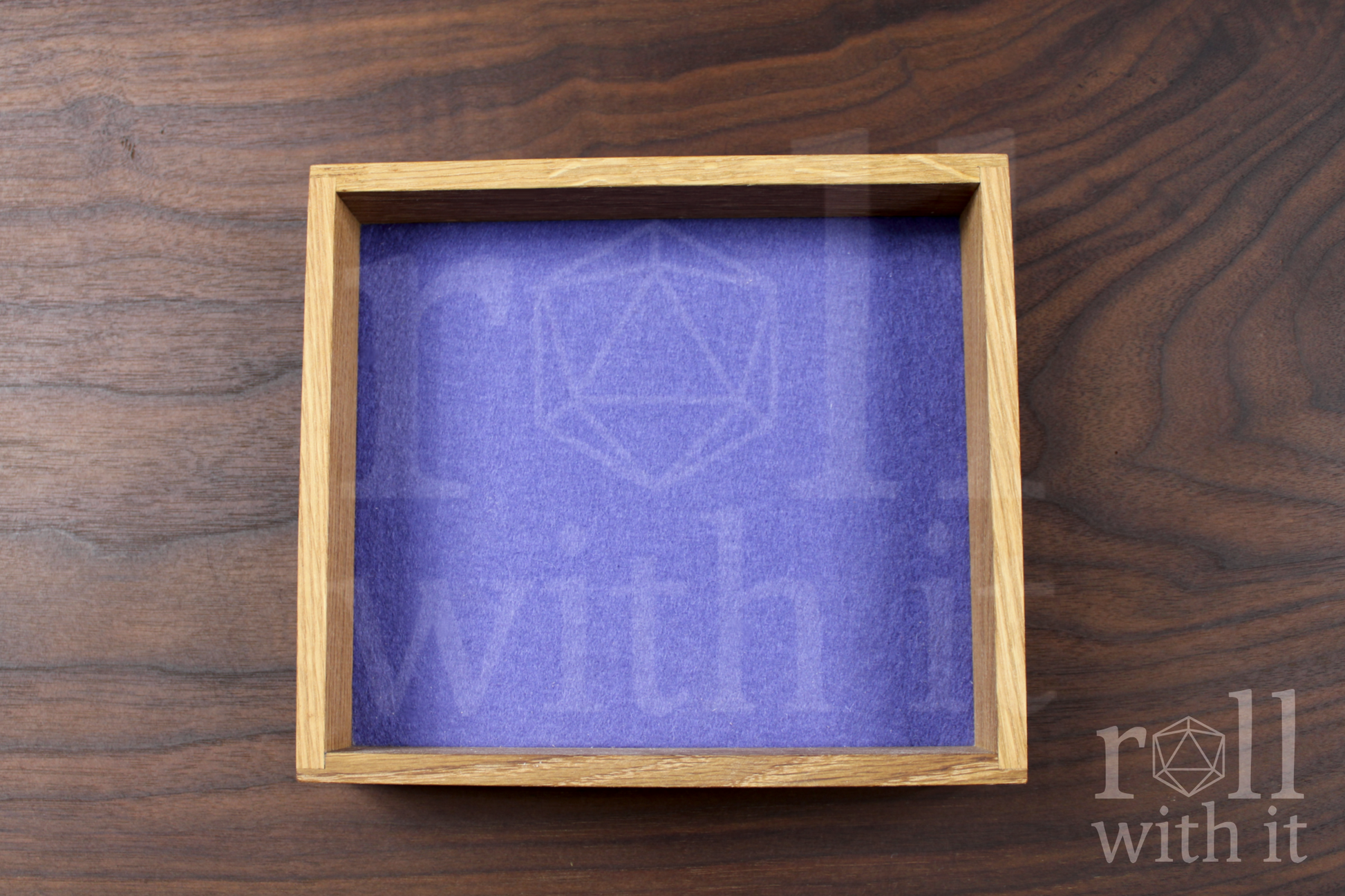 Solid oak DnD roleplaying dice throwing tray with a violet purple felt base, on a walnut worktop.