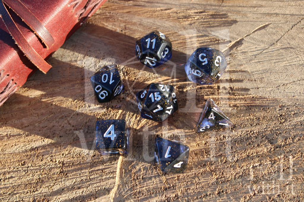 Set of deep blue polyhedral dice on a wooden surface with a leather bound journal in the background.