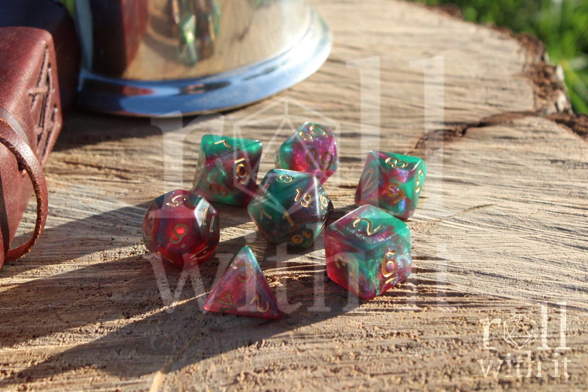 Set of colourful polyhedral rpg dice on a wooden surface with a leather journal in the background.