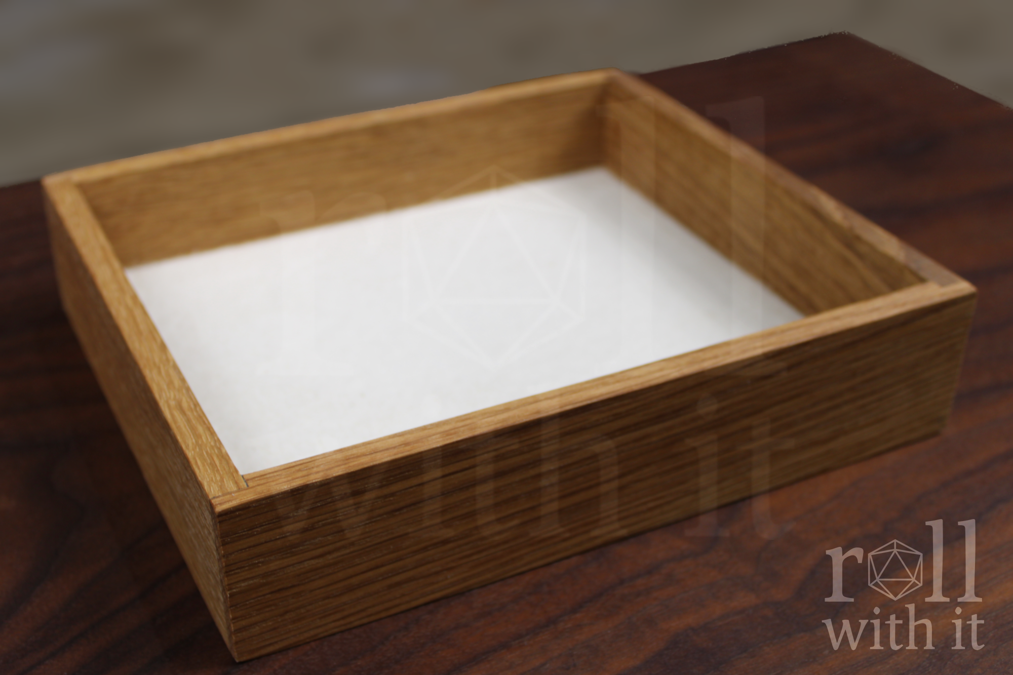 An empty Dungeons and Dragons DnD roleplaying dice tray with a white felt base made from white oak wood sat on a wooden table