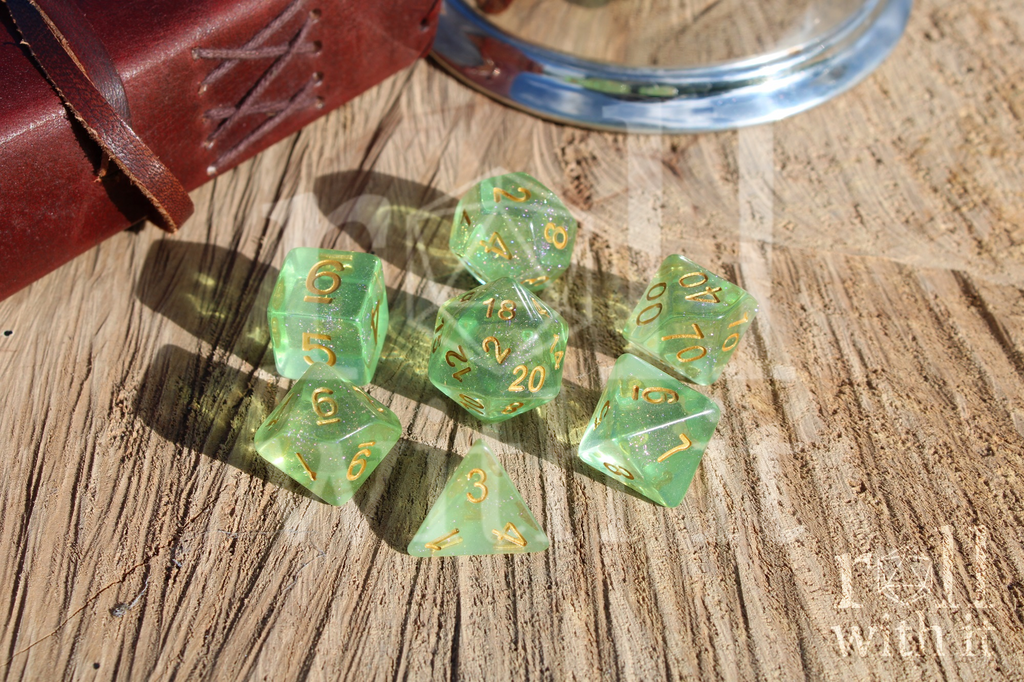 Green opal shimmering polyhedral dice set with gold numbers on a wooden surface.