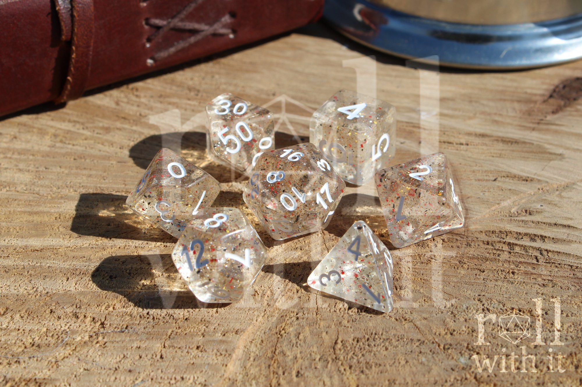Clear speckled polyhedral role playing dice set on a wooden surface with 'roll with it' text.