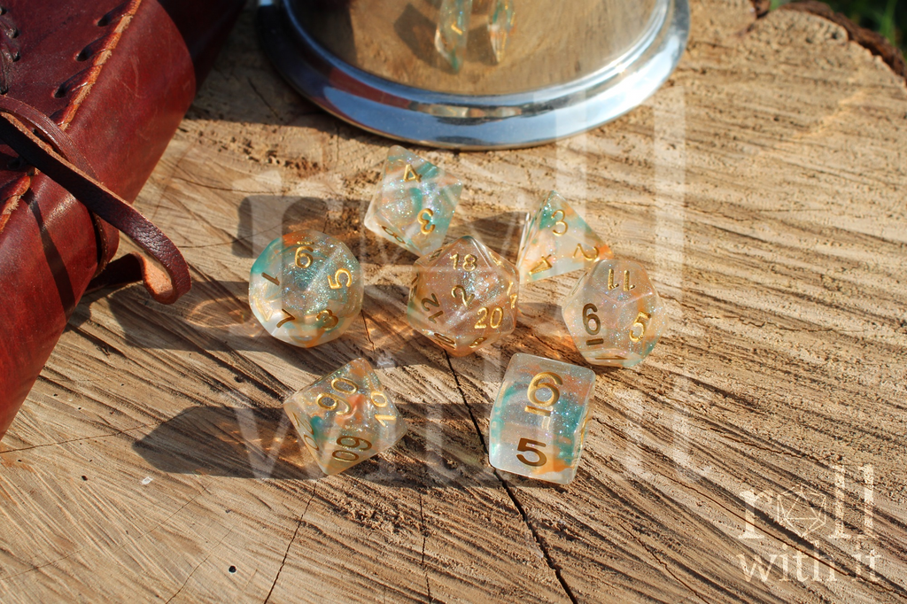 A set of 7 bright glitter filled orange and green tabletop roleplaying dice on a oak base with Dungeons and Dragons accessories in the background
