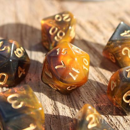 Set of amber honey gold brown polyhedral dice with gold numbers on a wooden surface