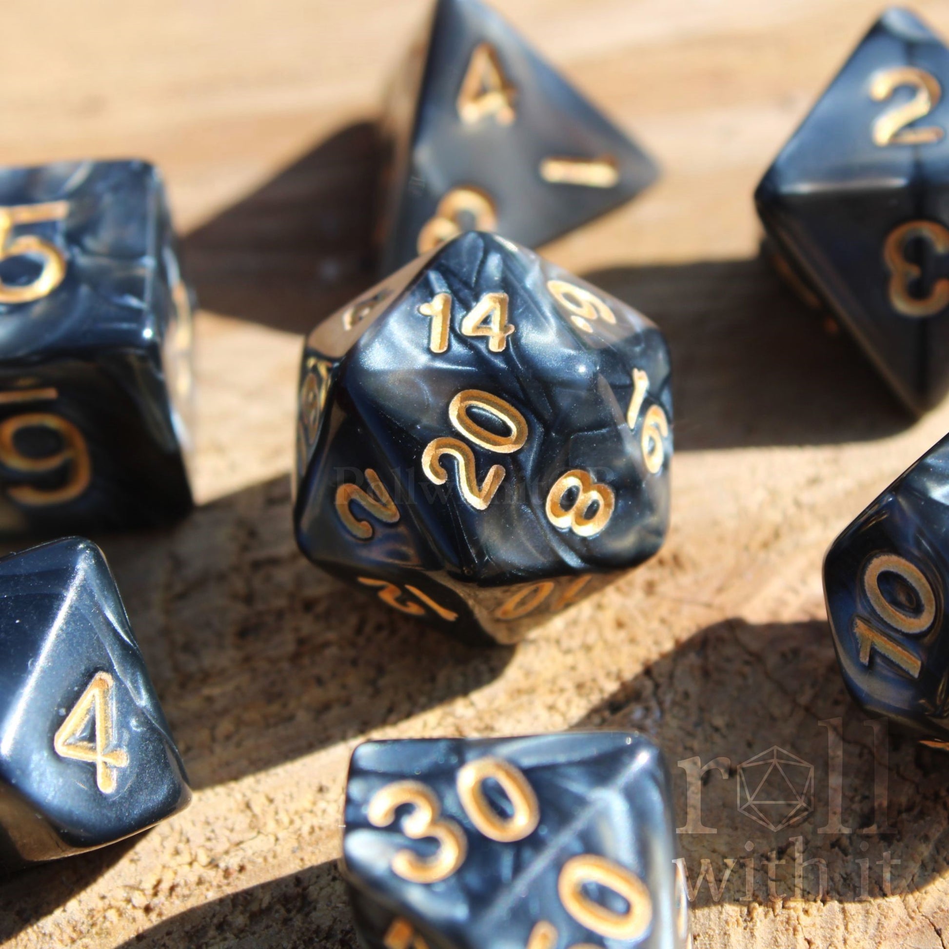 Set of shining black polyhedral dice with gold numbers on a wooden surface