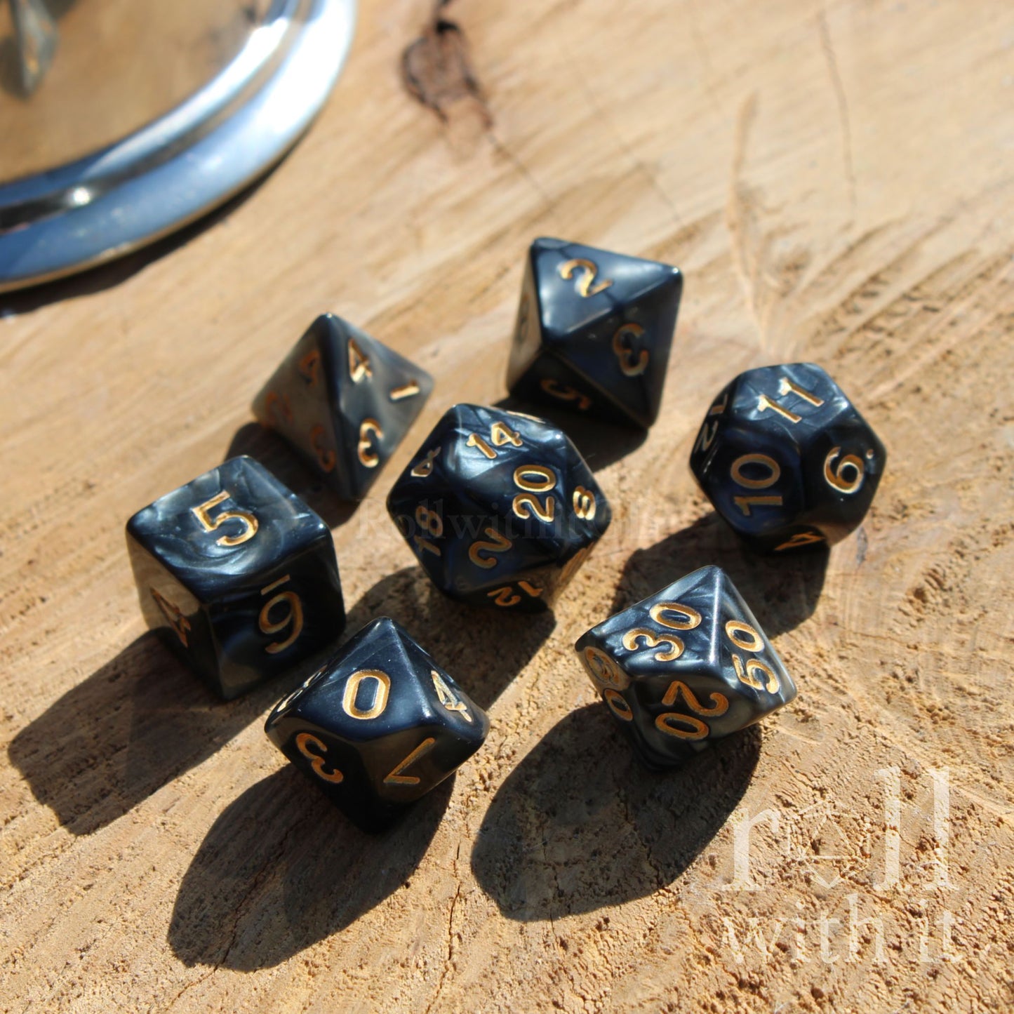 Set of black pearlescent shiny golden numbered set of DND dice on a wooden surface