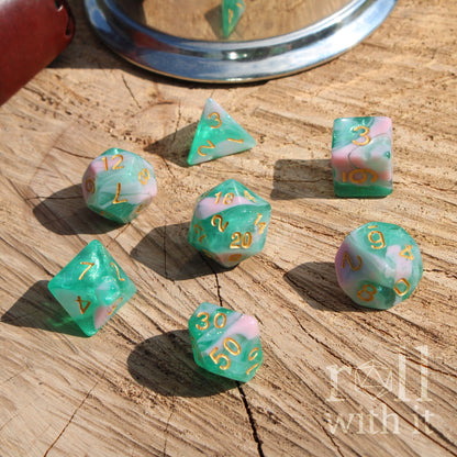 Set of Blue Green dice with gold lettering marbled on a wooden surface