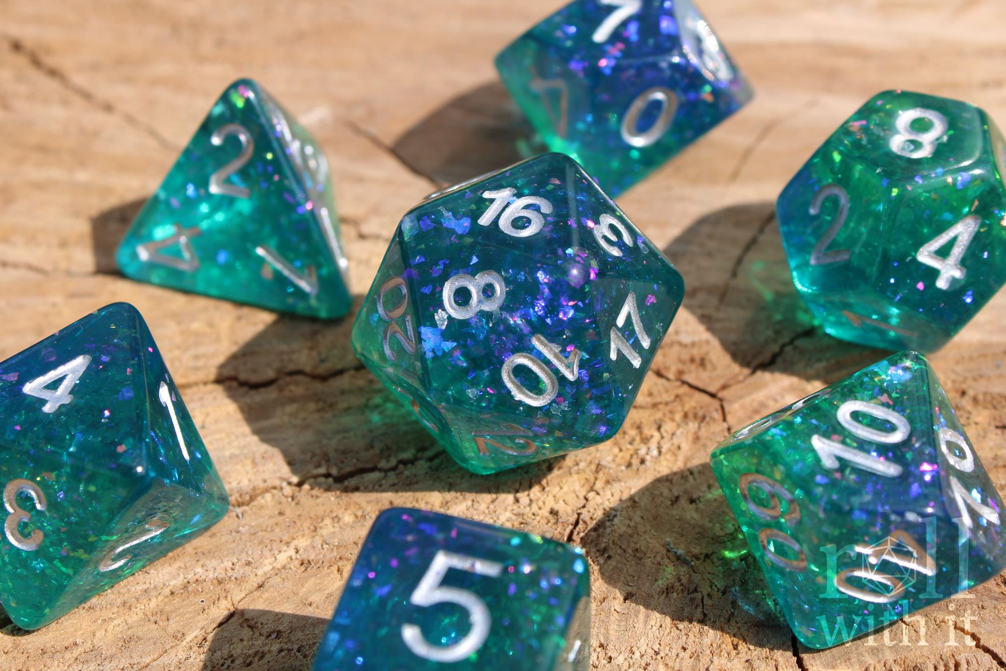Set of glittery and shining blue and green polyhedral DND dice with silver leaf inside on a wooden surface