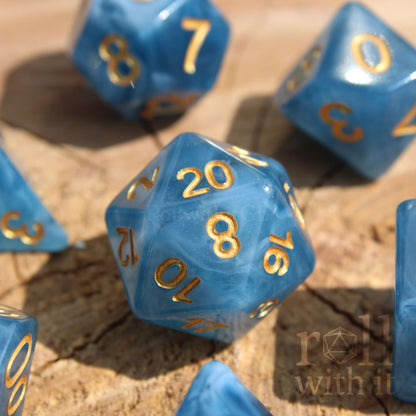 Set of jade blue translucent polyhedral roleplaying dice with gold numbers on a wooden surface
