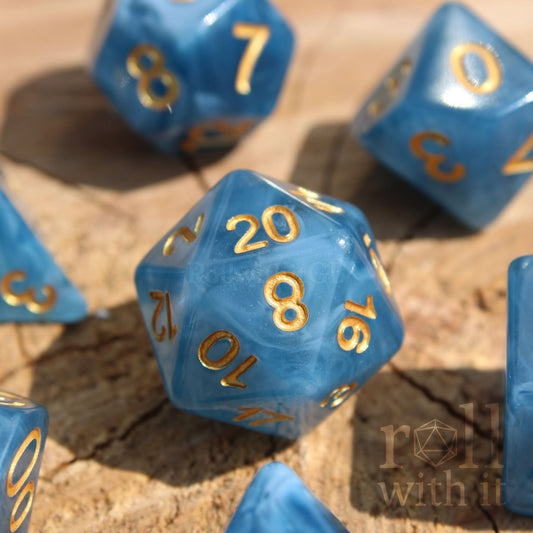 Set of jade blue translucent polyhedral roleplaying dice with gold numbers on a wooden surface