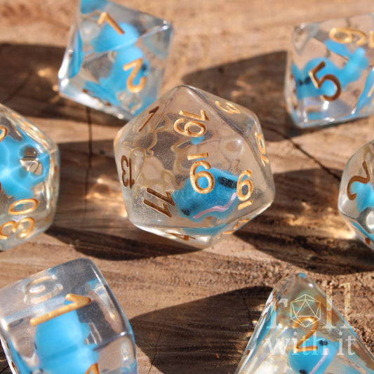 Set of clear polyhedral DnD dice with a small blue whale inside on a wooden surface