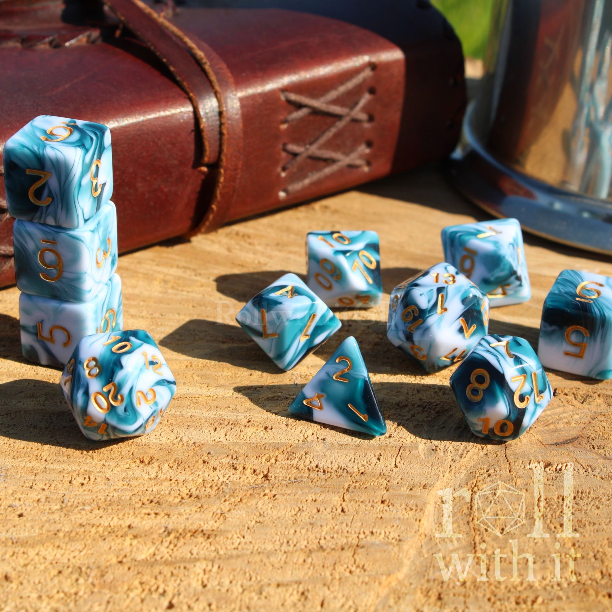 Blue and white dice set with gold numbers on a wooden surface, next to a leather book