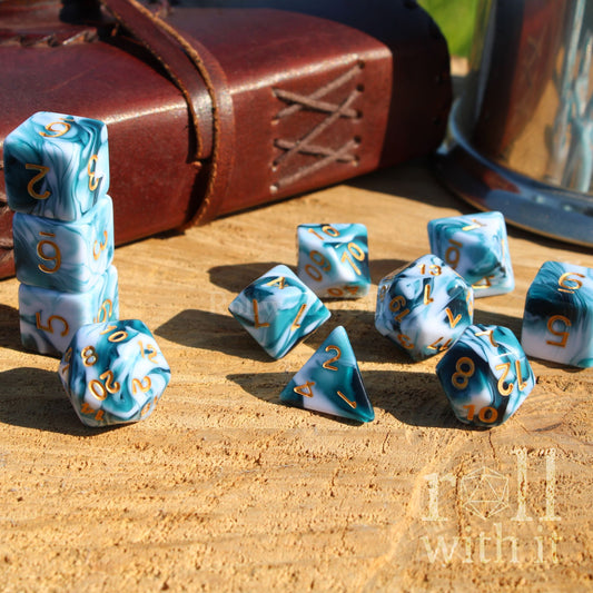 Blue and white dice set with gold numbers on a wooden surface, next to a leather book
