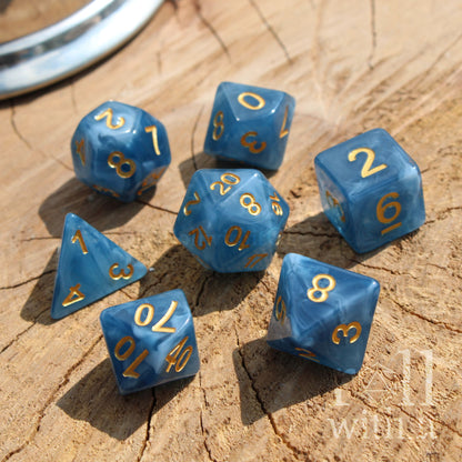 Set of blue polyhedral dice with gold numbers on a wooden surface
