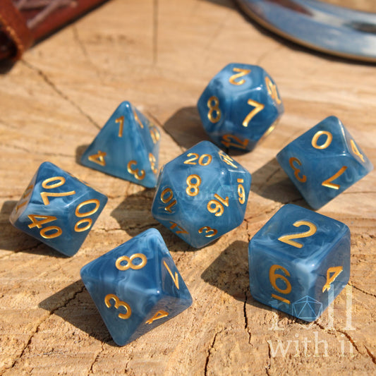 Blue swirling translucent polyhedral dice set with gold numbers on a wooden surface