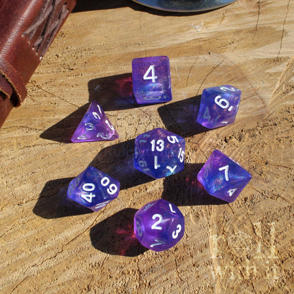 Top view of 7 purple and blue dice fantasy accessory set on a wooden surface with white numbers