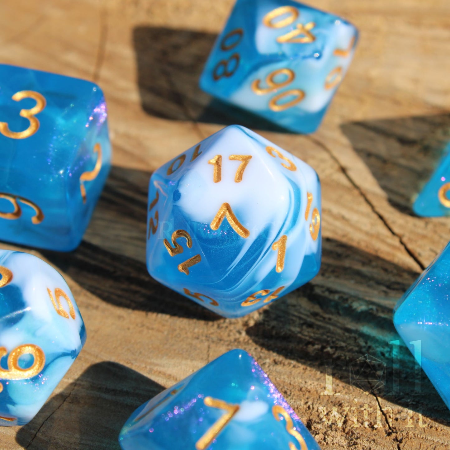 Set of blue and white glittery polyhedral dice with gold numbers on a wooden surface
