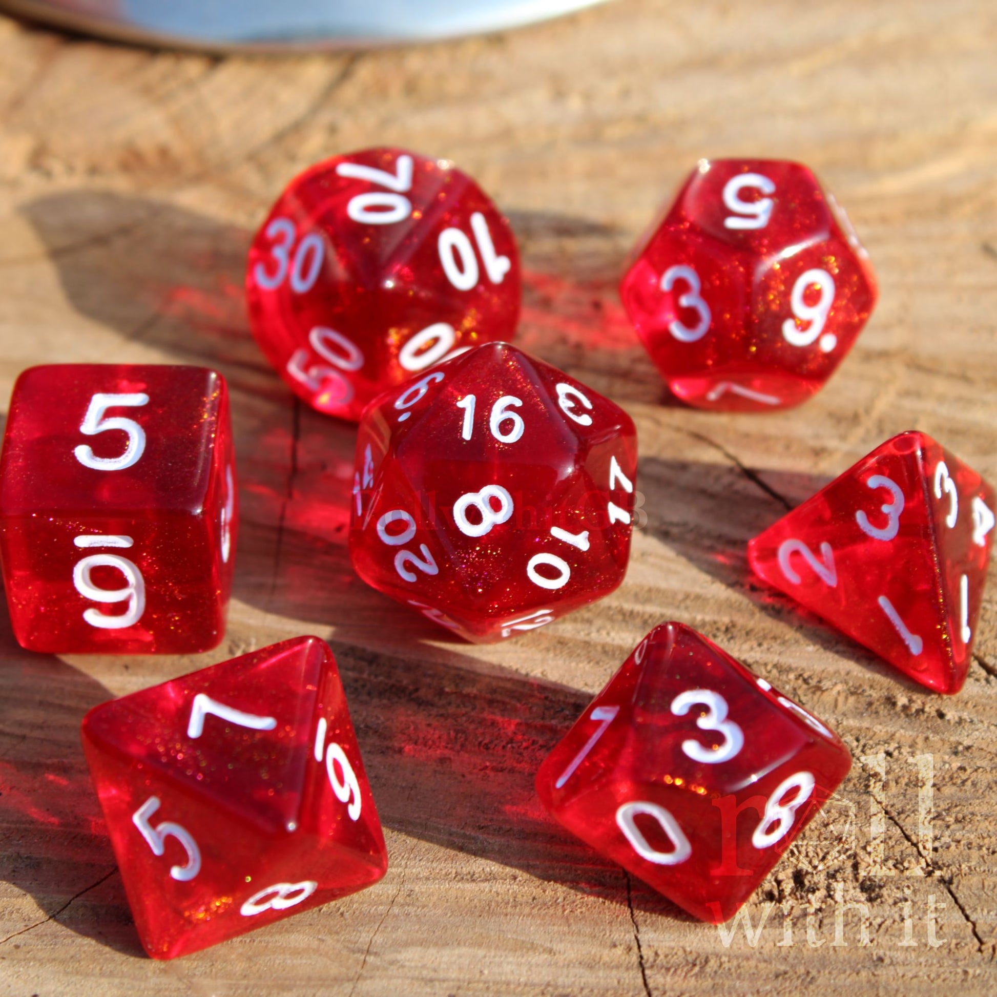 Set of 7 bright glittery scarlet red dice with white numbers on a wooden surface