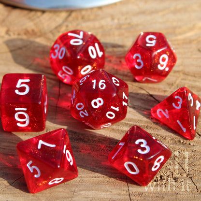 Set of 7 bright glittery scarlet red dice with white numbers on a wooden surface