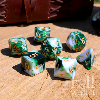 Set of bright dark green and white dice with gold numbers on a wooden surface.