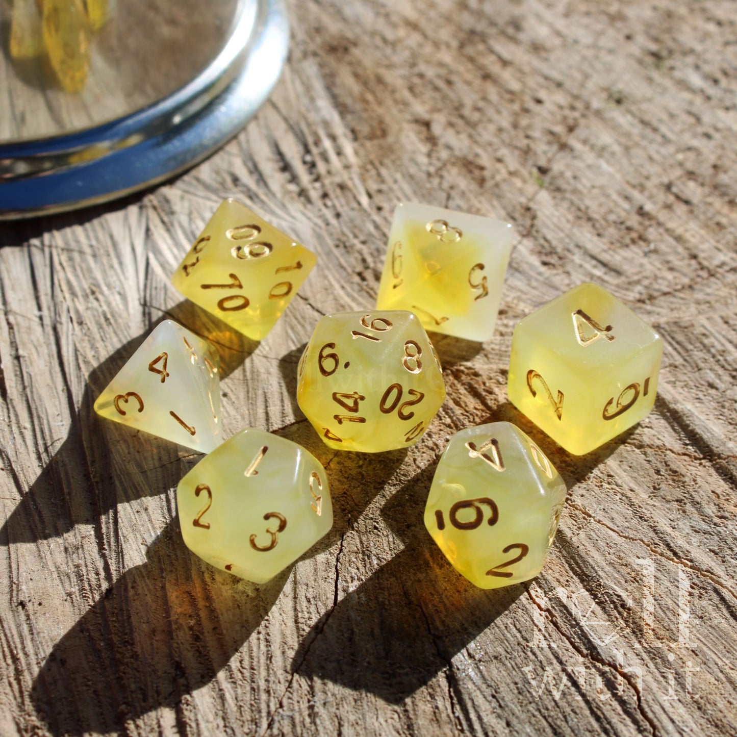 Set of 7 polyhedral yellow RPG accessory polyhedral dice on a wooden surface with gold letters
