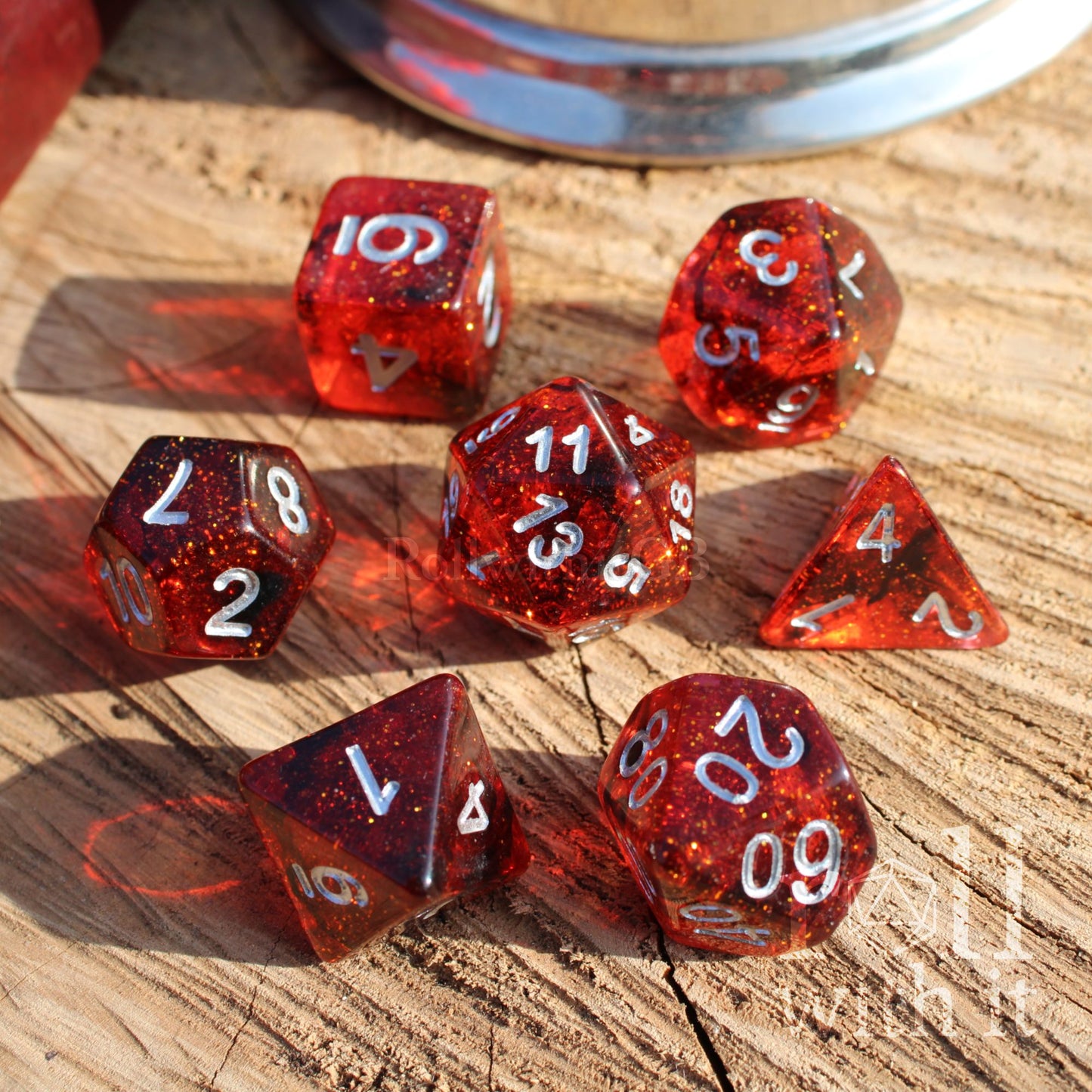 Set of red glittery reflective polyhedral D&D dice on a wooden surface