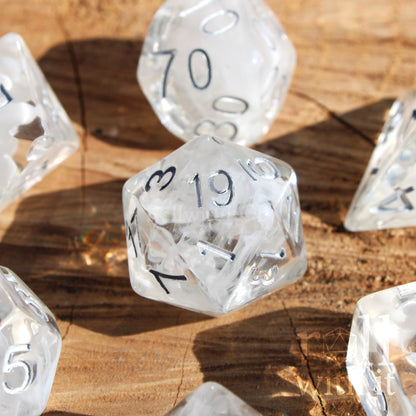 Clear white smoke polyhedral dice with silver numbers on a wooden surface
