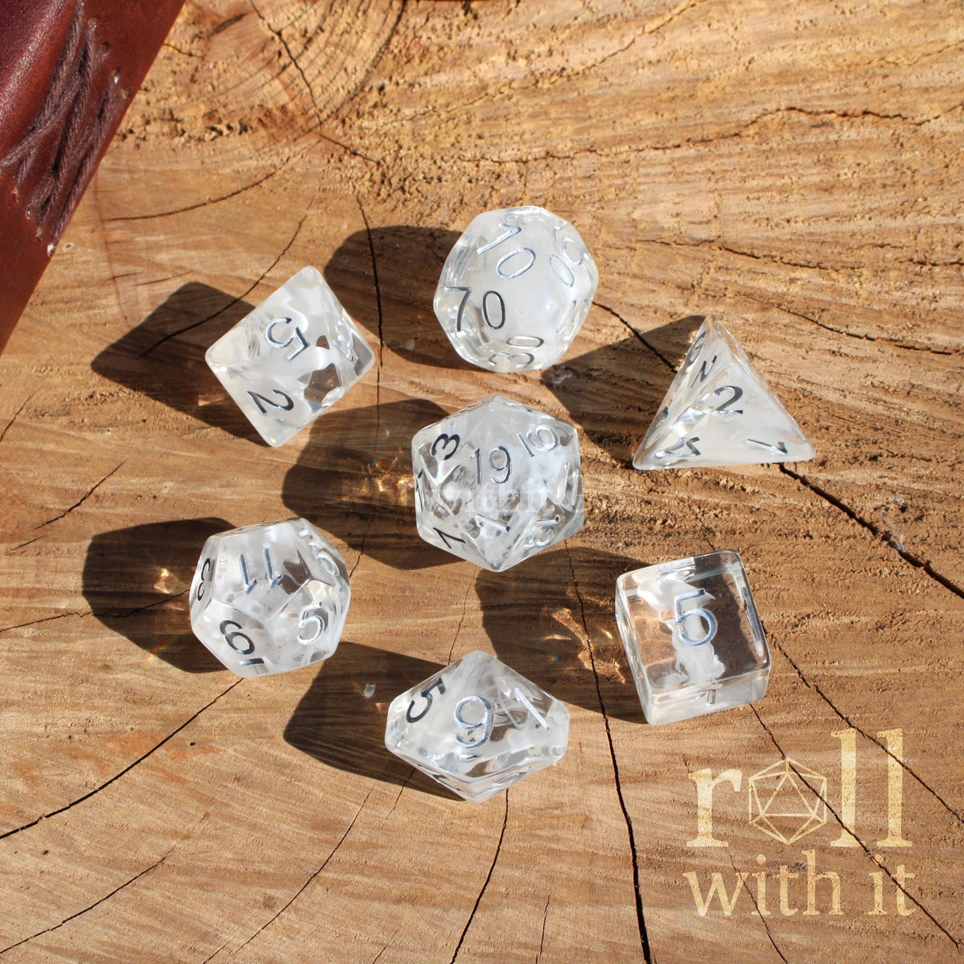 Clear white wisp swirling dice with numbers on a wooden surface, featuring 'roll with it' branding.