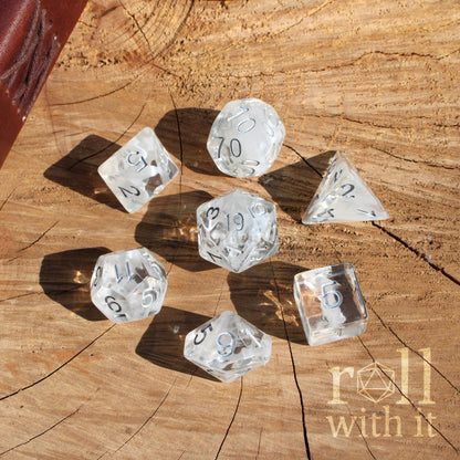 Clear white wisp swirling dice with numbers on a wooden surface, featuring 'roll with it' branding.