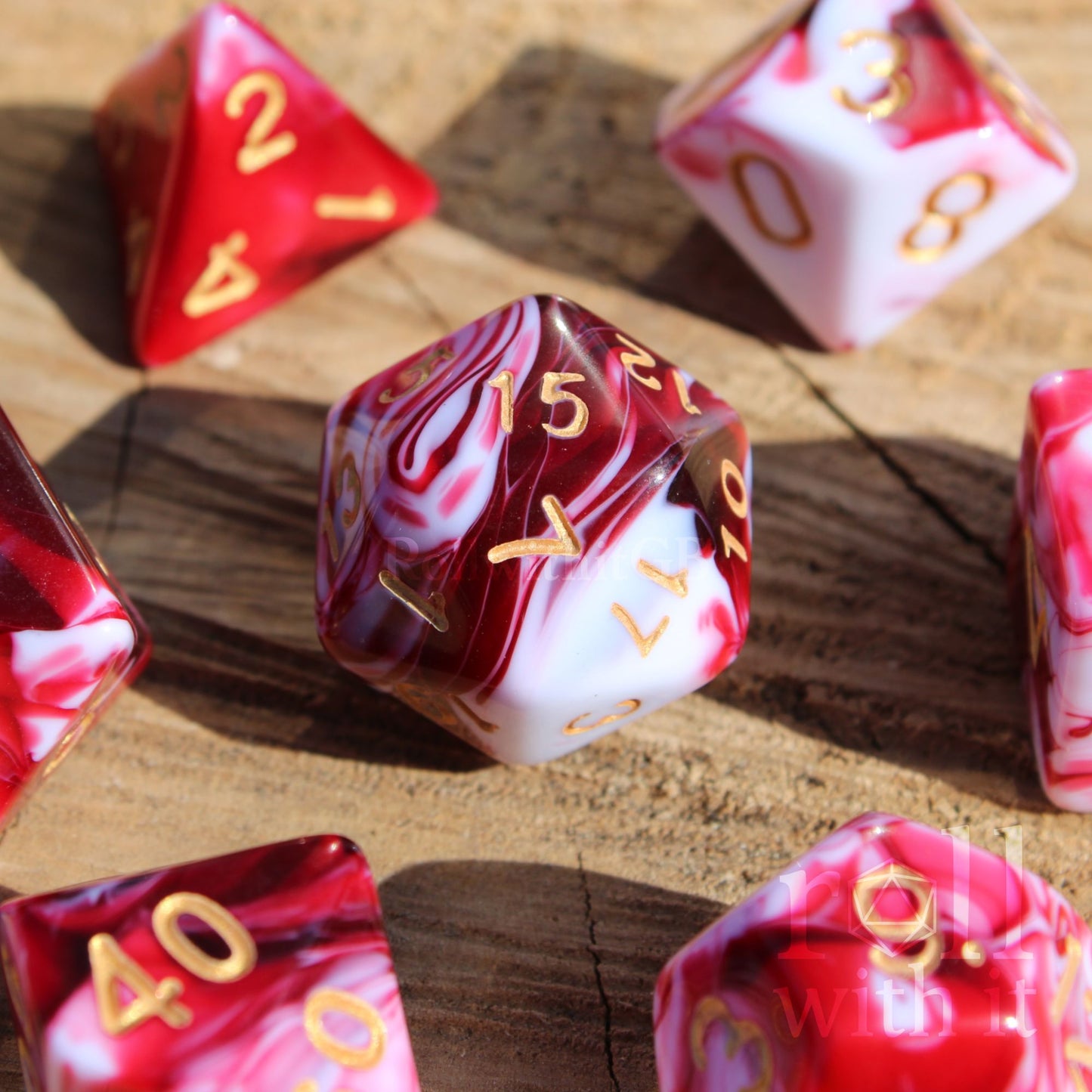 A set of 7 creamy cherry red and white swirling polyhedral tabletop roleplaying dice on an oak base.
