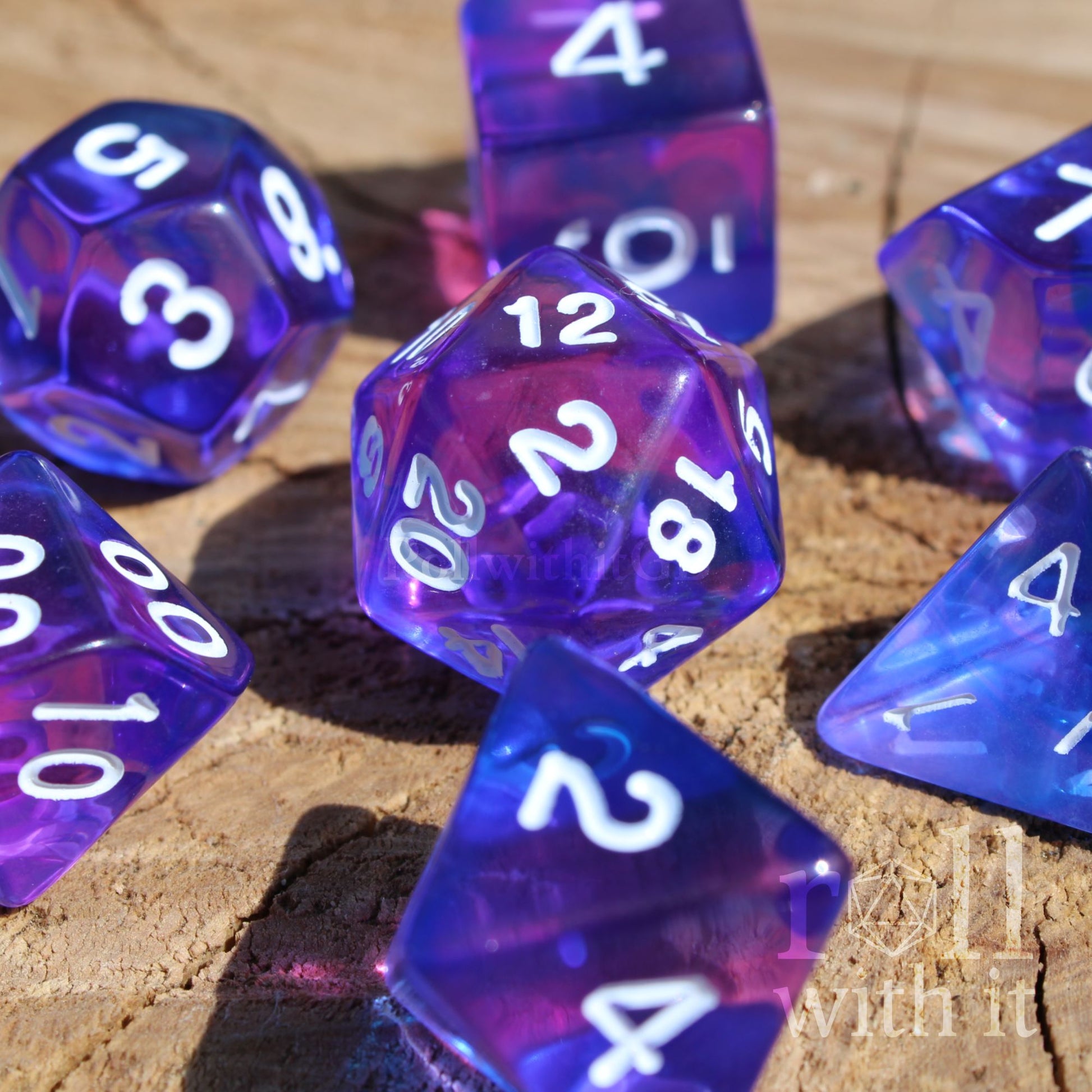 Set of clear blue and indigo purple polyhedral roleplaying dice with white numbers on a wooden surface