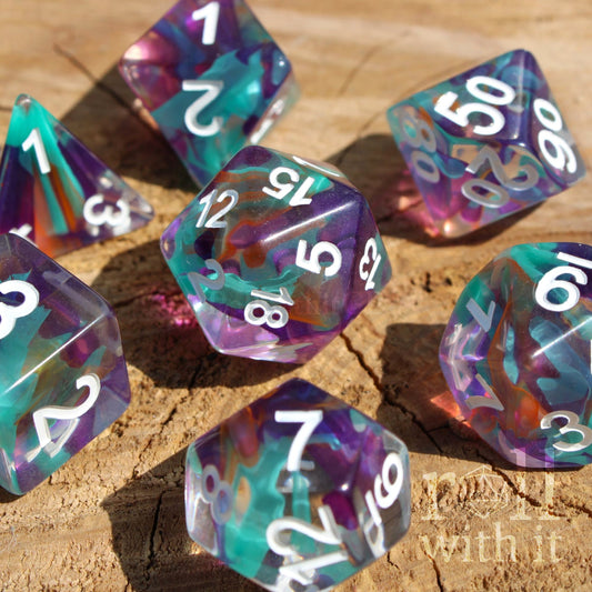 Set of 7 colourful aquamarine blue, lilac and ginger toned multicoloured polyhedral DND roleplaying dice with white numbers on a wooden surface