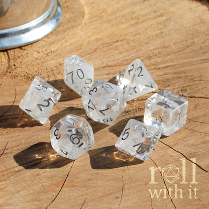 Clear dice with numbers on a wooden surface, featuring the 'roll with it' logo.