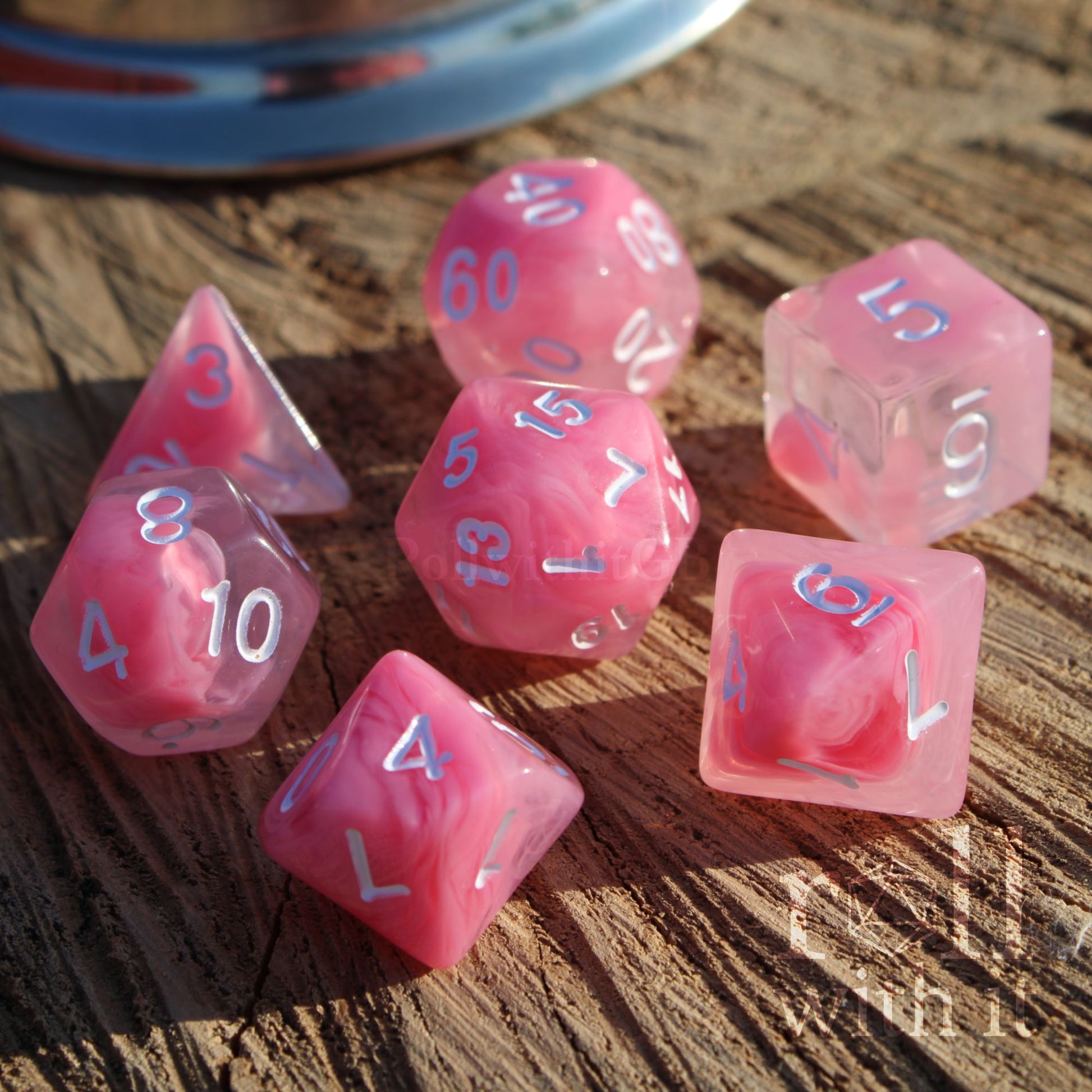 A set of 7 cute bright cloudy pink D&D dice on a wooden surface with white numbers