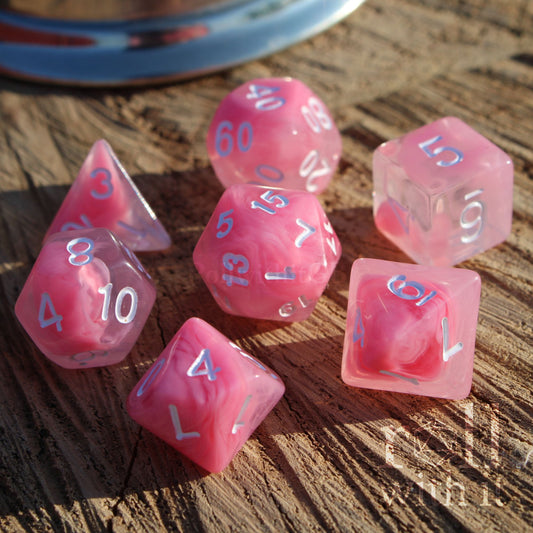 A set of 7 cute bright cloudy pink D&D dice on a wooden surface with white numbers